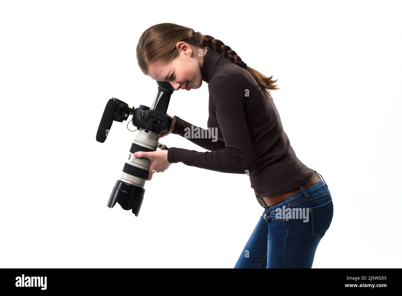 La bella fotografo ragazza con fotocamera reflex professionale in posa su uno sfondo bianco in studio. Concetto di apprendimento fotografico, studio, formazione Foto Stock