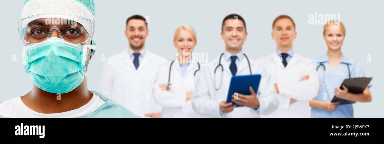 primo piano di chirurgo indiano in maschera e medici Foto Stock