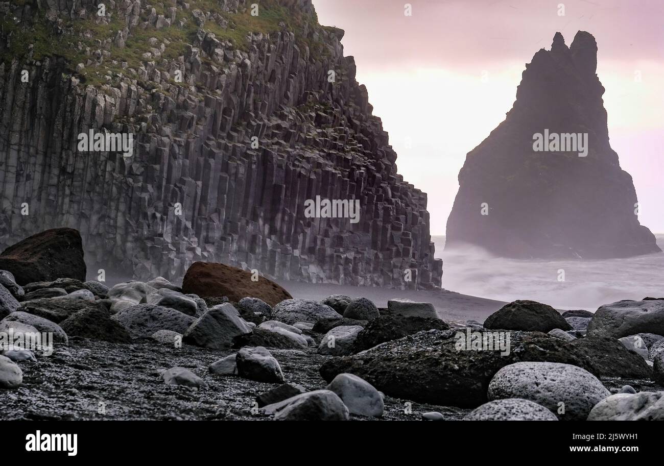 Schwarzer Strand Reynisfjara mit Basaltsäulen, Foto in der Morgendämmerung aufgenommen. Im Hintergrund einer der Reynisdrangar-Felsen. Foto Stock