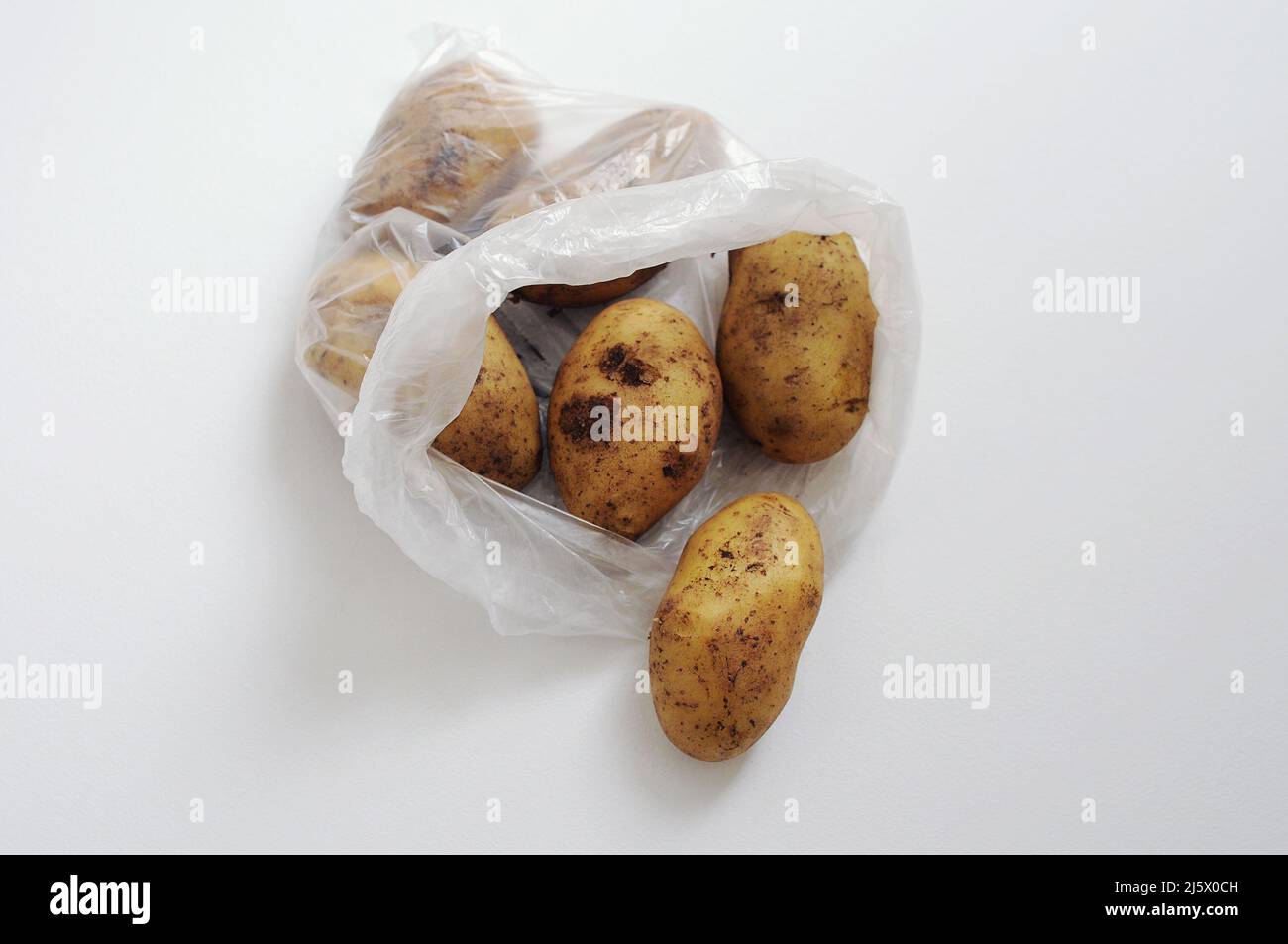 Patate in un sacchetto di plastica. Cibo confezionato in cellophane su sfondo bianco. Imballaggi non ecologici Foto Stock