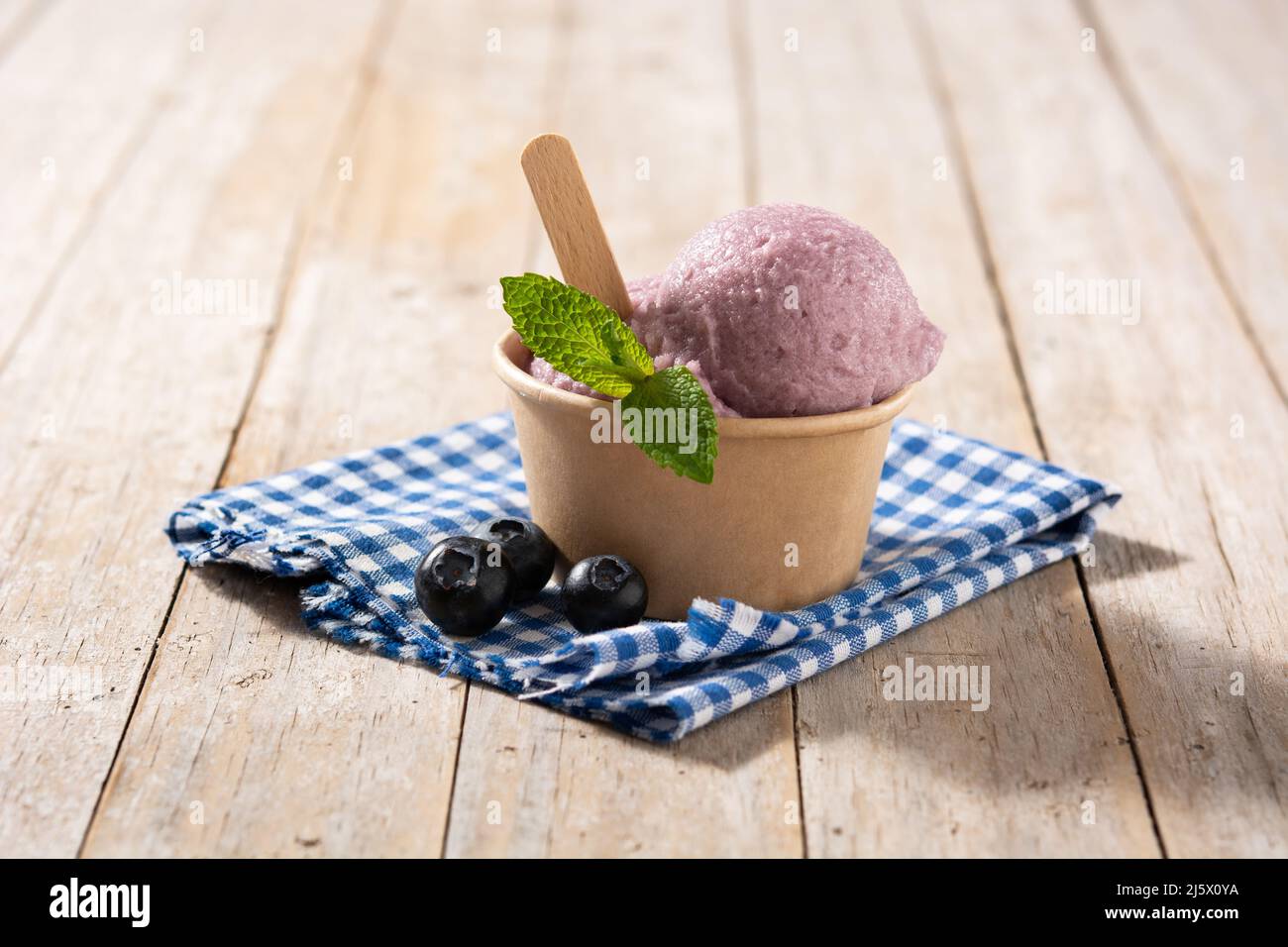 Cucchiaio per gelato al mirtillo su tavola di legno Foto Stock