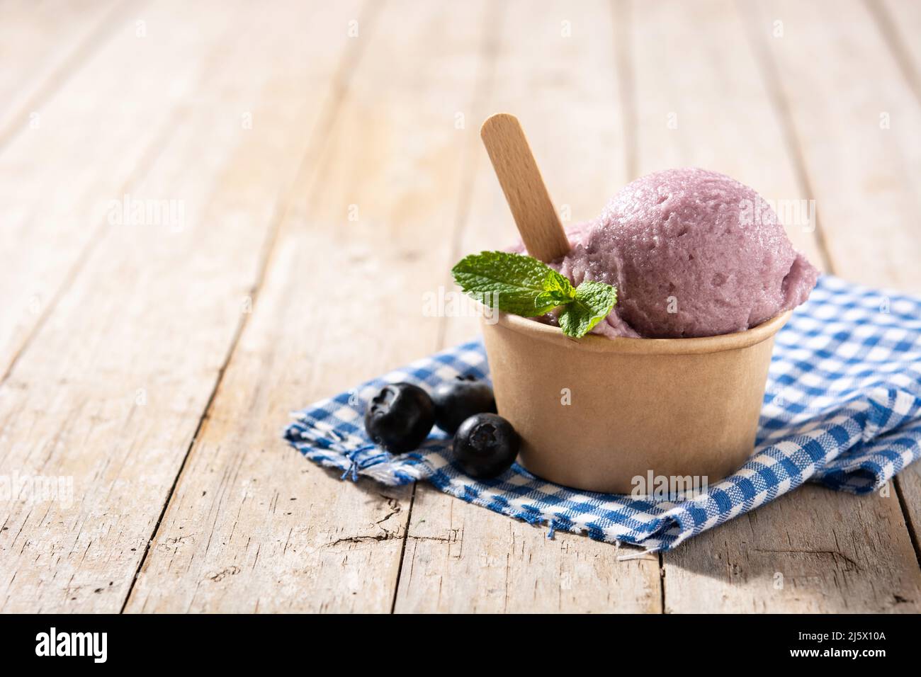 Cucchiaio per gelato al mirtillo su tavola di legno Foto Stock