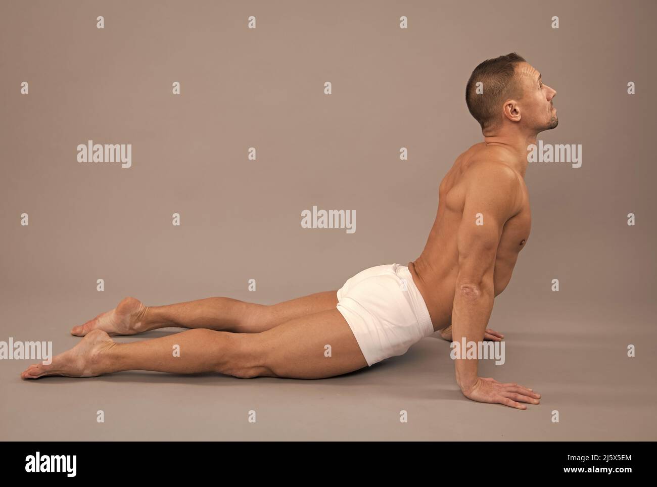 Yogi man do back-bending asana cobra yoga posa sfondo grigio, posizione del corpo Foto Stock
