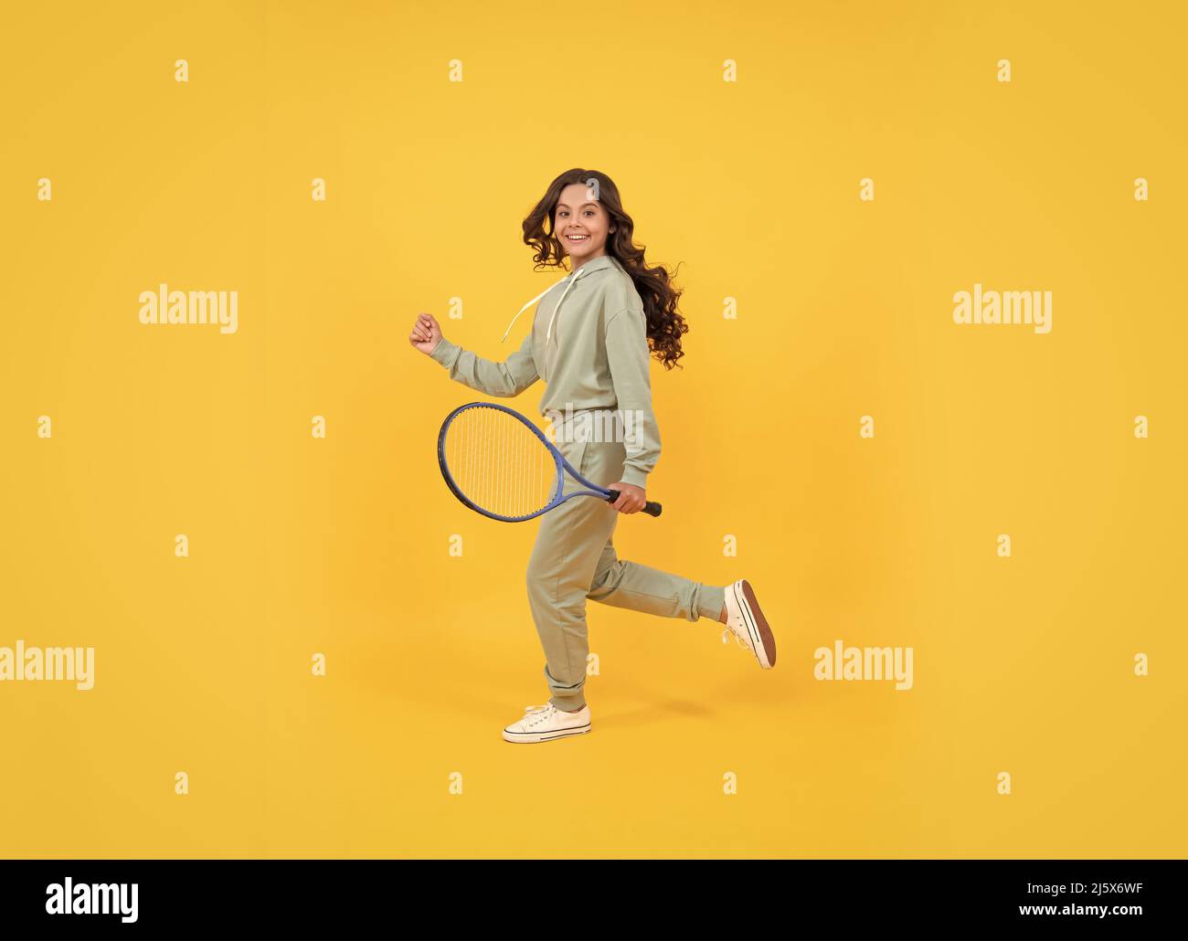 happy energico bambino salto in abbigliamento sportivo con racchetta da tennis in corsa al successo, infanzia attiva. Foto Stock