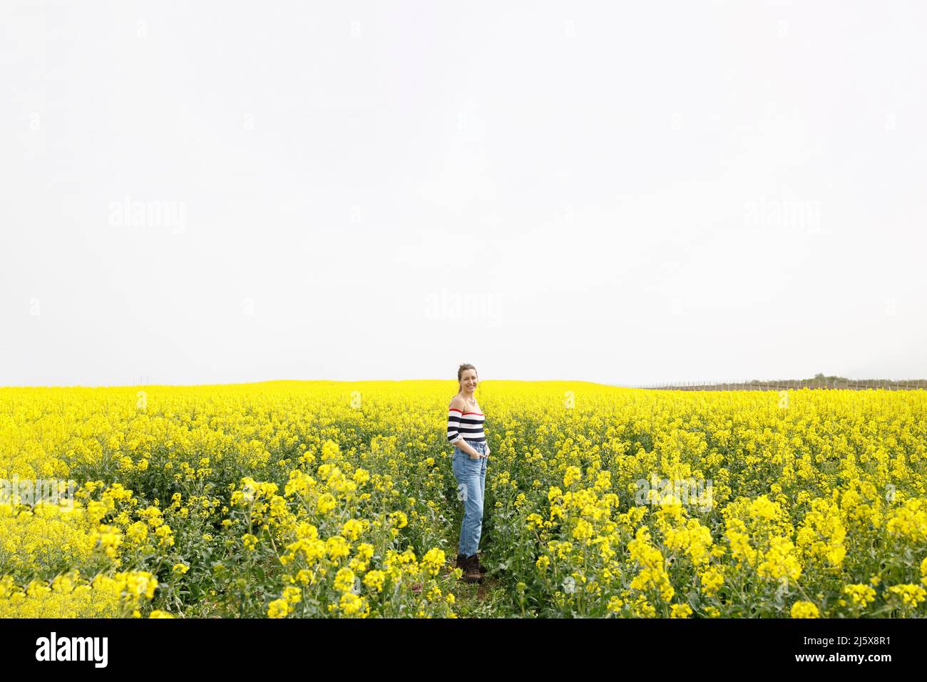 Una donna felice in piedi in un campo giallo Foto Stock