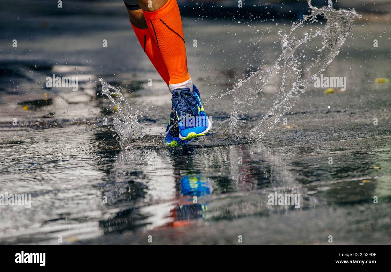 gambe atleta maschile puddle running. spruzzi d'acqua Foto Stock