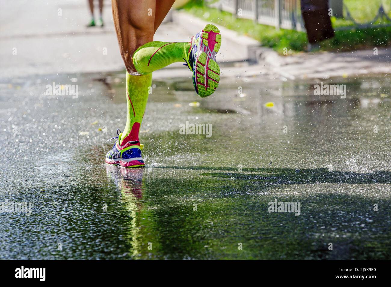 gambe femmina runner in calze a compressione running su asfalto bagnato Foto Stock