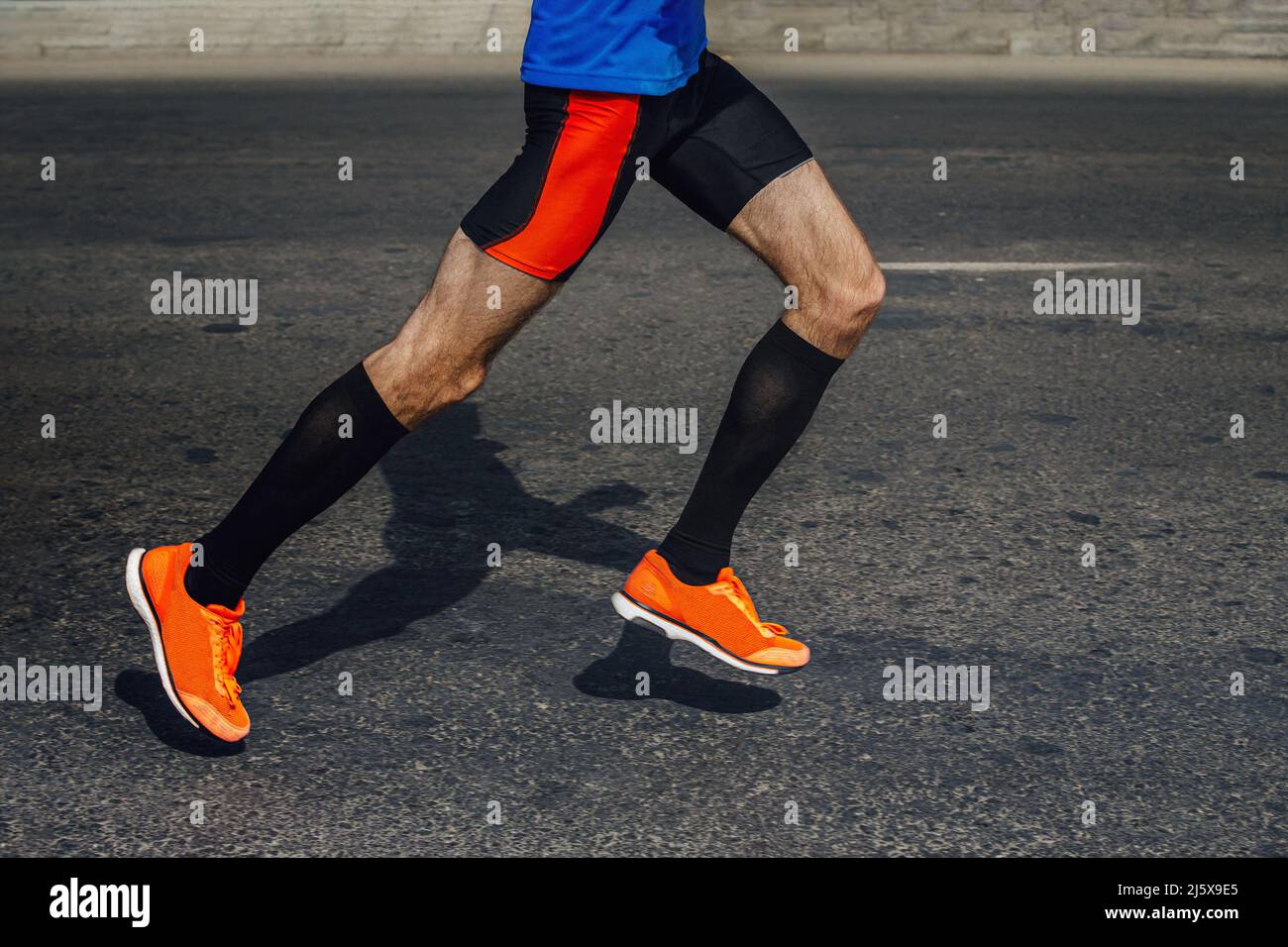 gambe atleta in calze a compressione correre maratona su asfalto Foto Stock