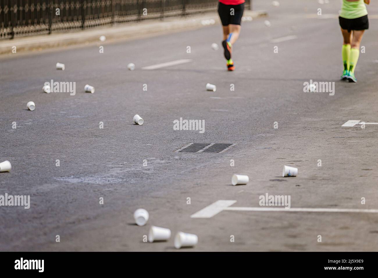 punto di gara maratona acqua. tazze di plastica usate su asfalto Foto Stock