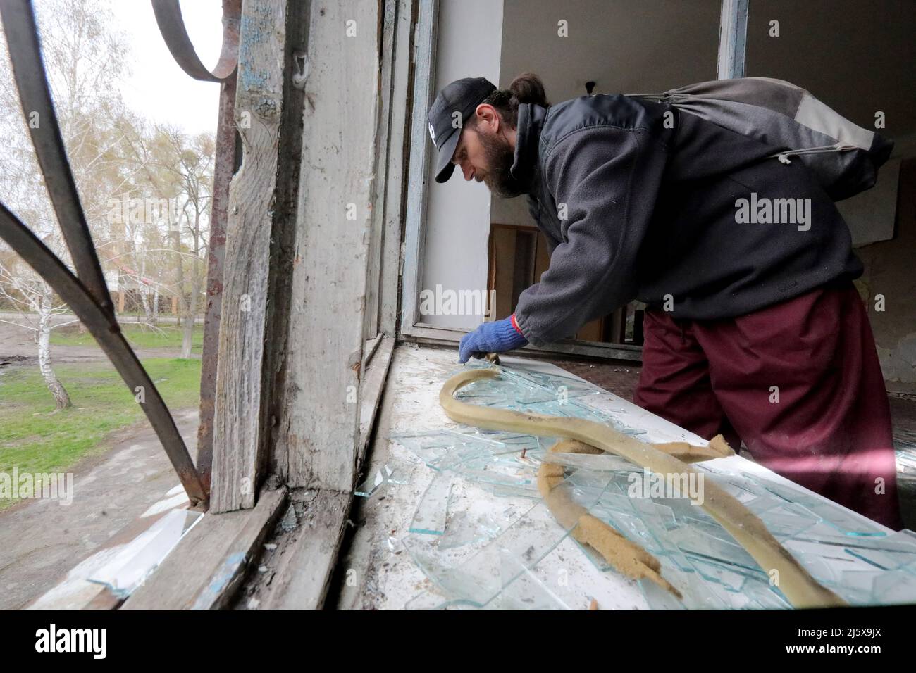 BORODIANKA, UCRAINA - 26 APRILE 2022 - Un uomo prende le barrette di vetro in un centro di risorse inclusive danneggiato durante l'invasione russa durante il restauro Foto Stock
