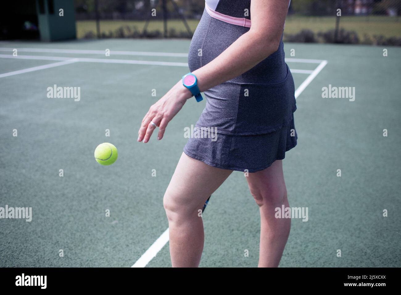 Donna incinta che rimbalza sul campo da tennis Foto Stock