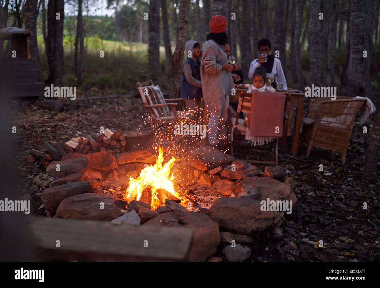 Famiglia relax a tavola accanto al fuoco in boschi Foto Stock