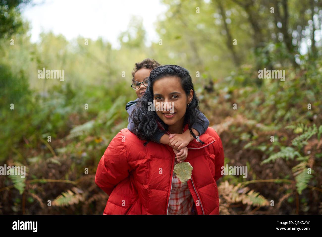 Ritratto madre piggybacking figlio su escursione in boschi Foto Stock