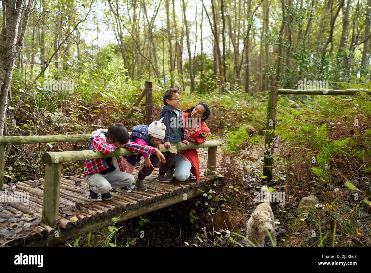 Madre e bambini con cane su passerella in legno Foto Stock