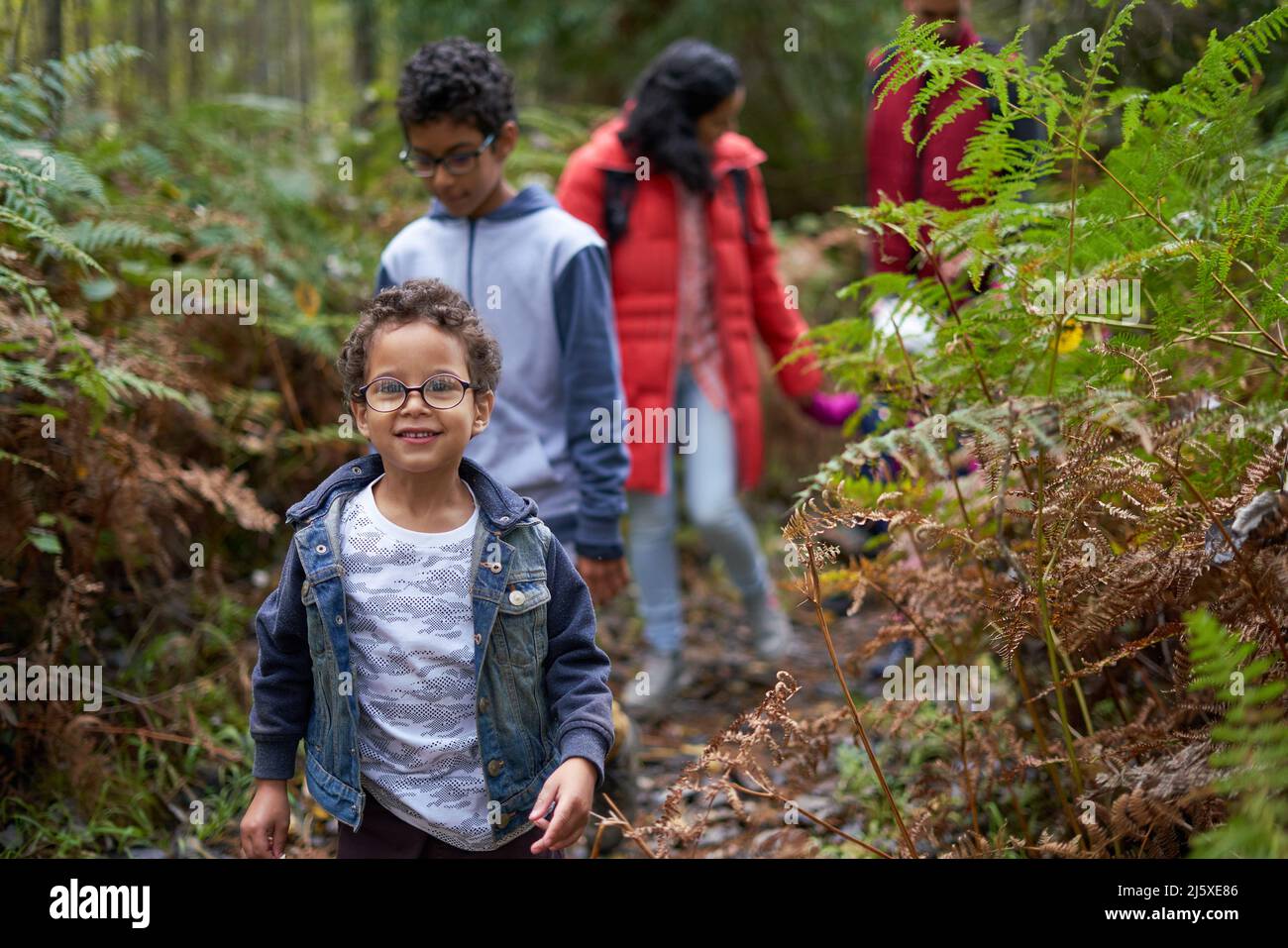 Ritratto carino ragazzo escursioni con la famiglia sul sentiero in boschi Foto Stock