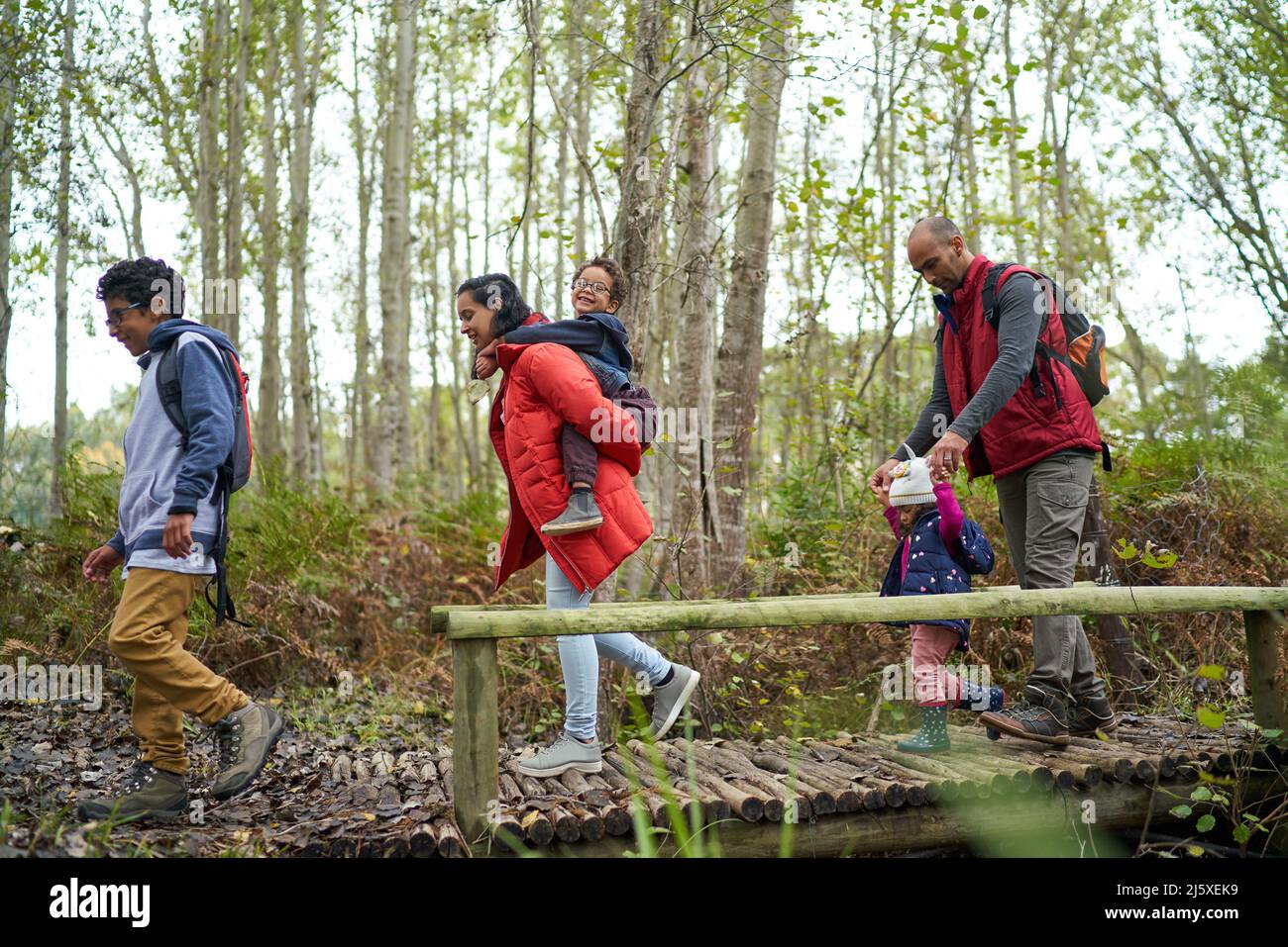 Famiglia che attraversa il ponte pedonale su un'escursione in boschi Foto Stock
