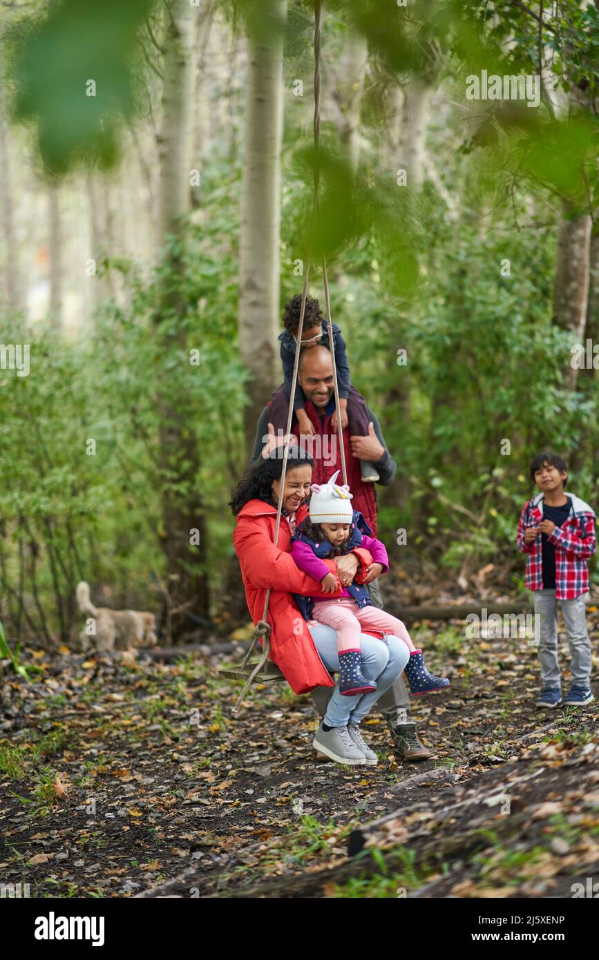 Famiglia giocosa sul swing in boschi Foto Stock
