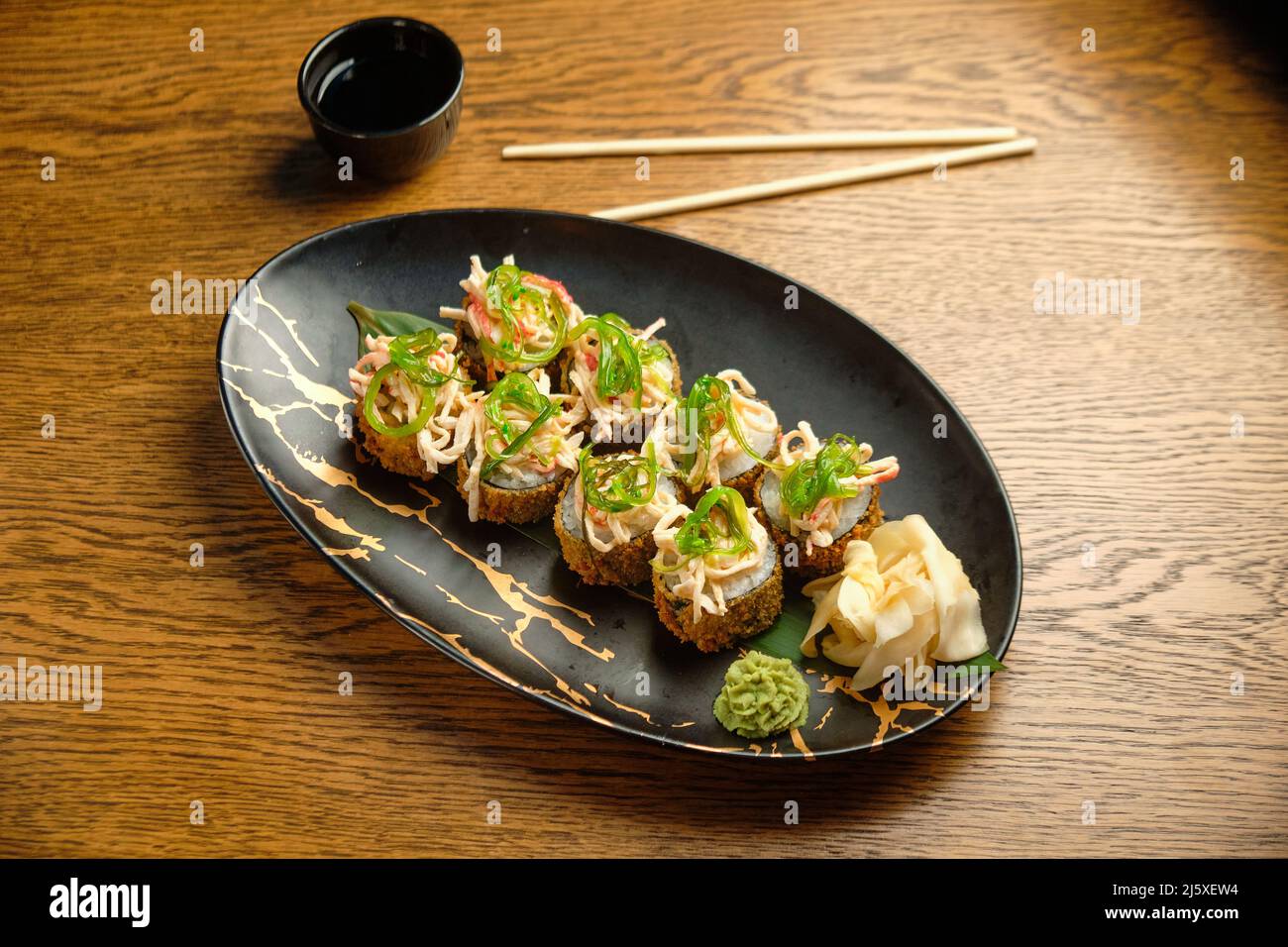 Un set di sushi caldi con salmone, avocado e semi di sesamo nero da vicino. Fuoco selettivo Foto Stock