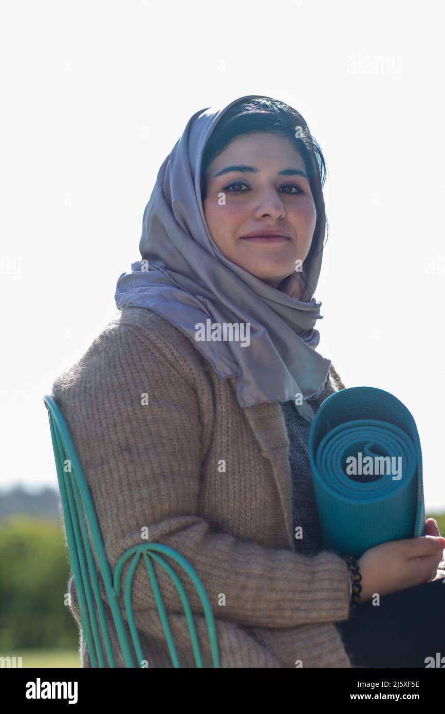 Ritratto sorridente giovane musulmana in hijab con stuoia yoga Foto Stock