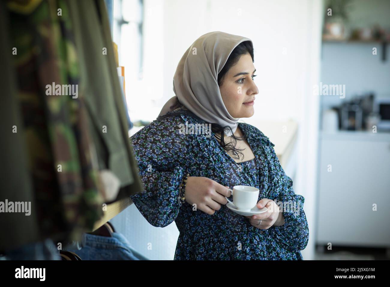 Giovane donna musulmana pensierosa in hijab bere caffè Foto Stock