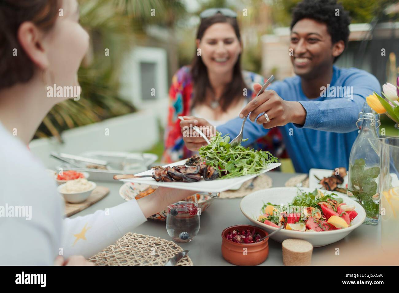 Amici felici che godono il pranzo vegetariano al tavolo del patio Foto Stock