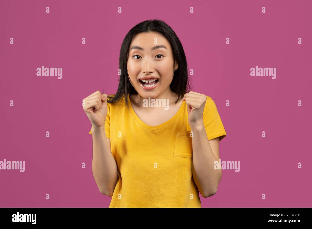 Sì, concetto di realizzazione. La donna asiatica gioiva e gridava, celebrando la vittoria su sfondo violetto Foto Stock