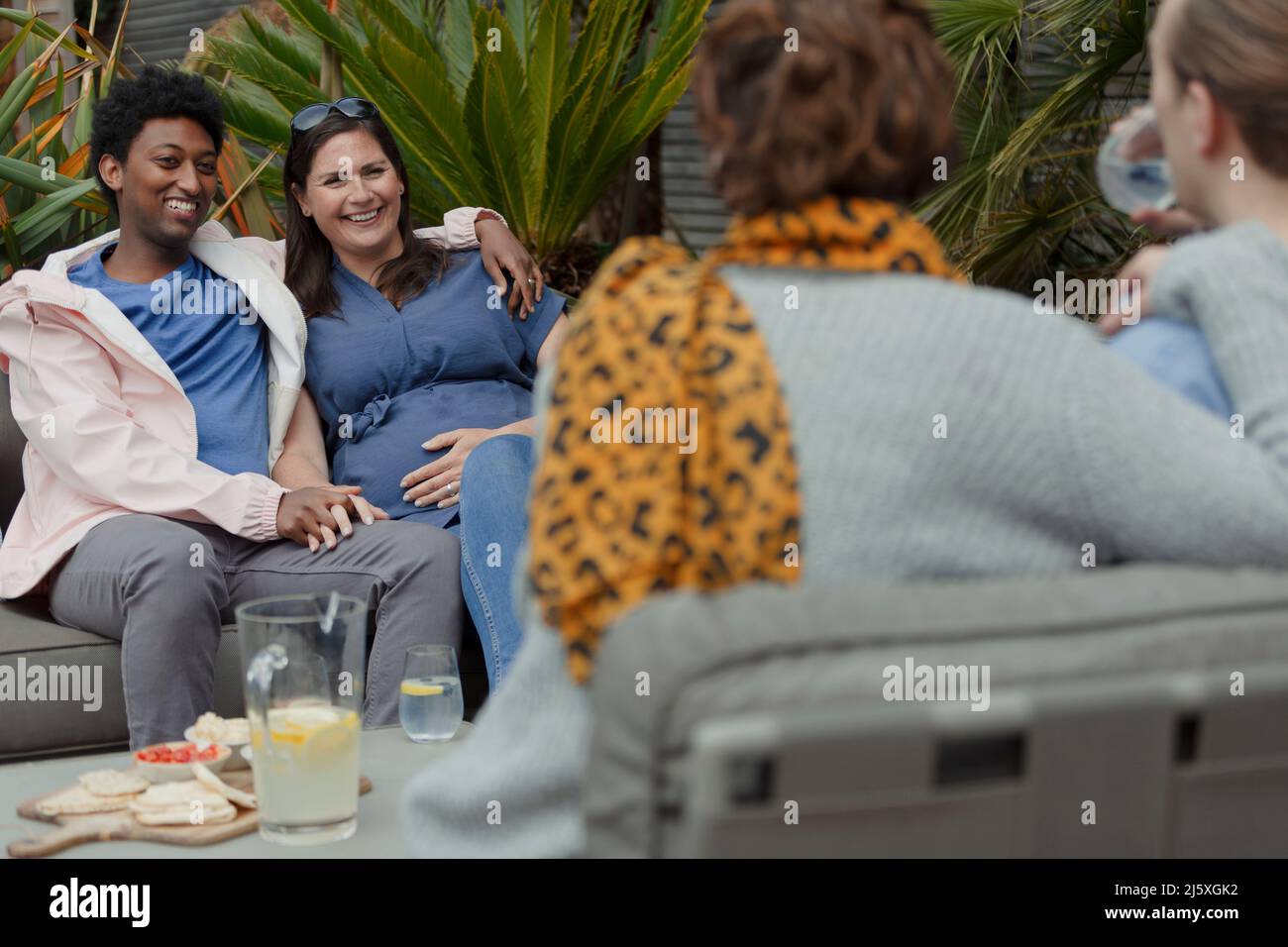 Coppia incinta che pende fuori con gli amici sul patio Foto Stock