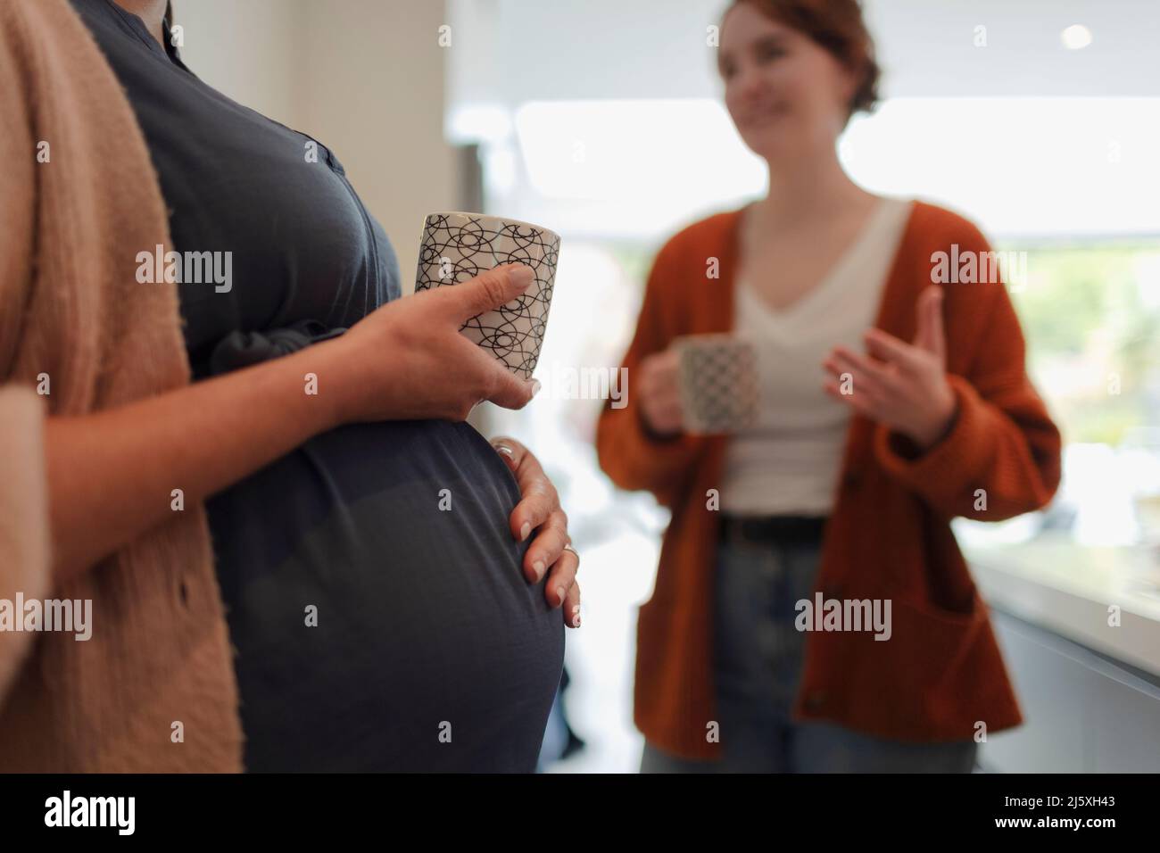 Donna incinta e amico che parla e beve il tè Foto Stock