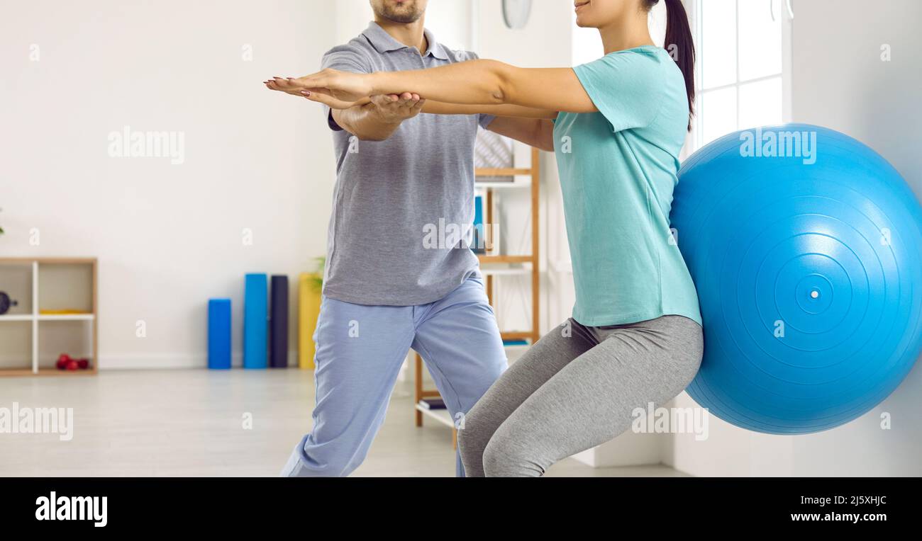 Giovane paziente femminile con fisioterapista fa esercizi per la schiena con l'aiuto di fit ball. Foto Stock