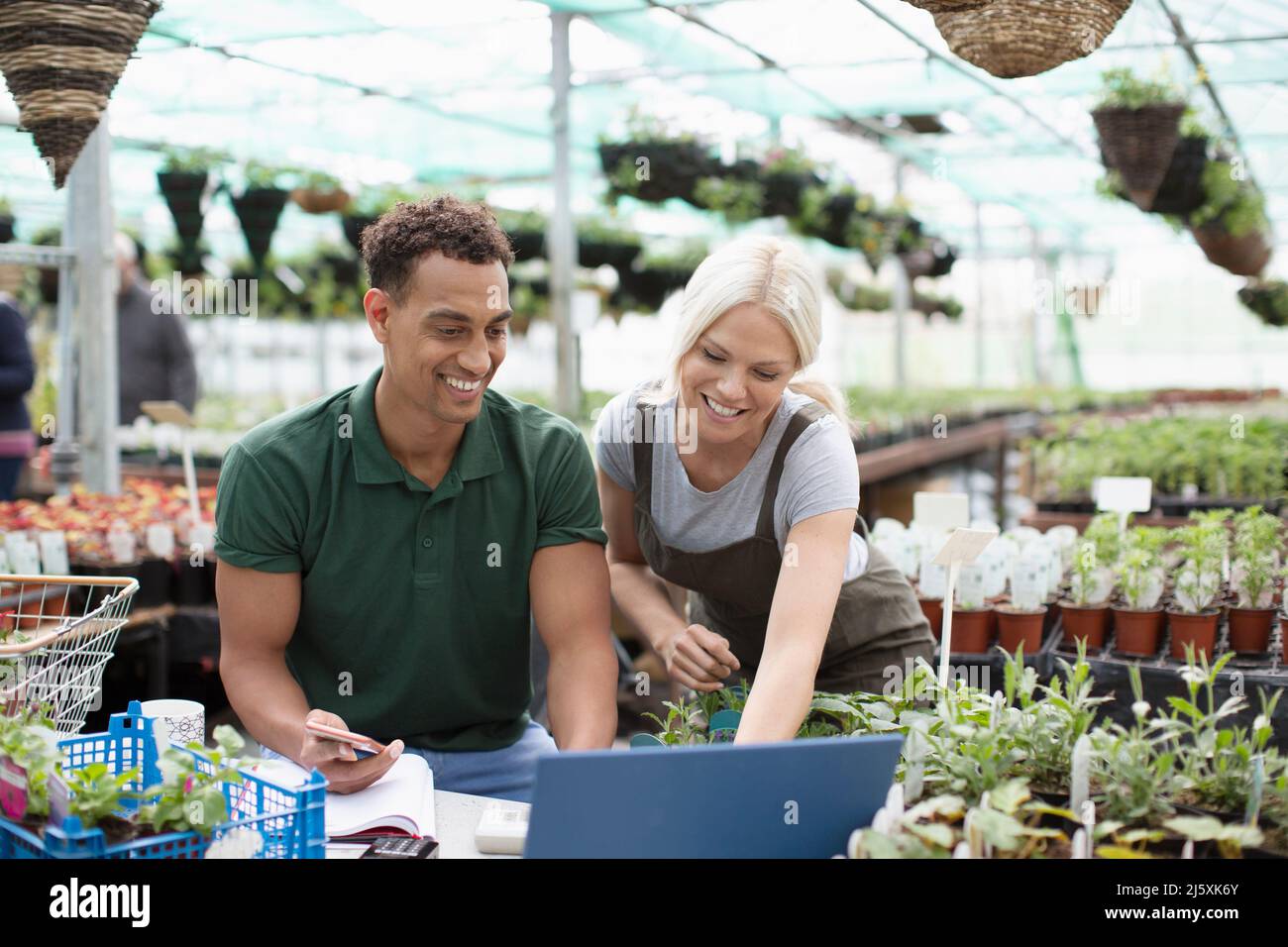 Proprietari di negozi di giardino felice che lavorano al laptop in serra Foto Stock