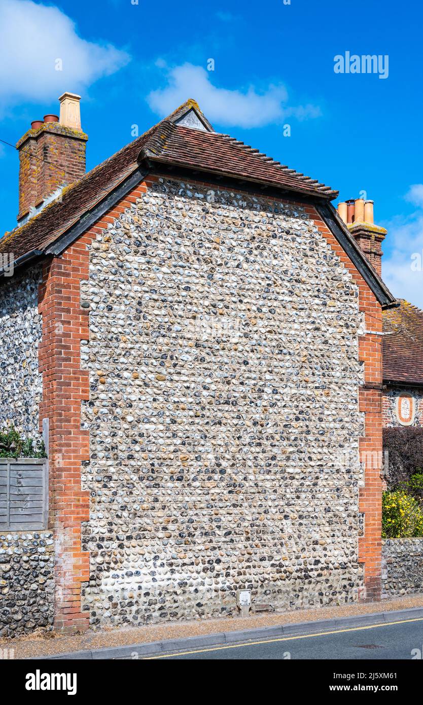 Vecchio muro con mix di pietra focaia e mattoni rossi, su un grande muro sul lato di un edificio in Inghilterra, Regno Unito. Foto Stock