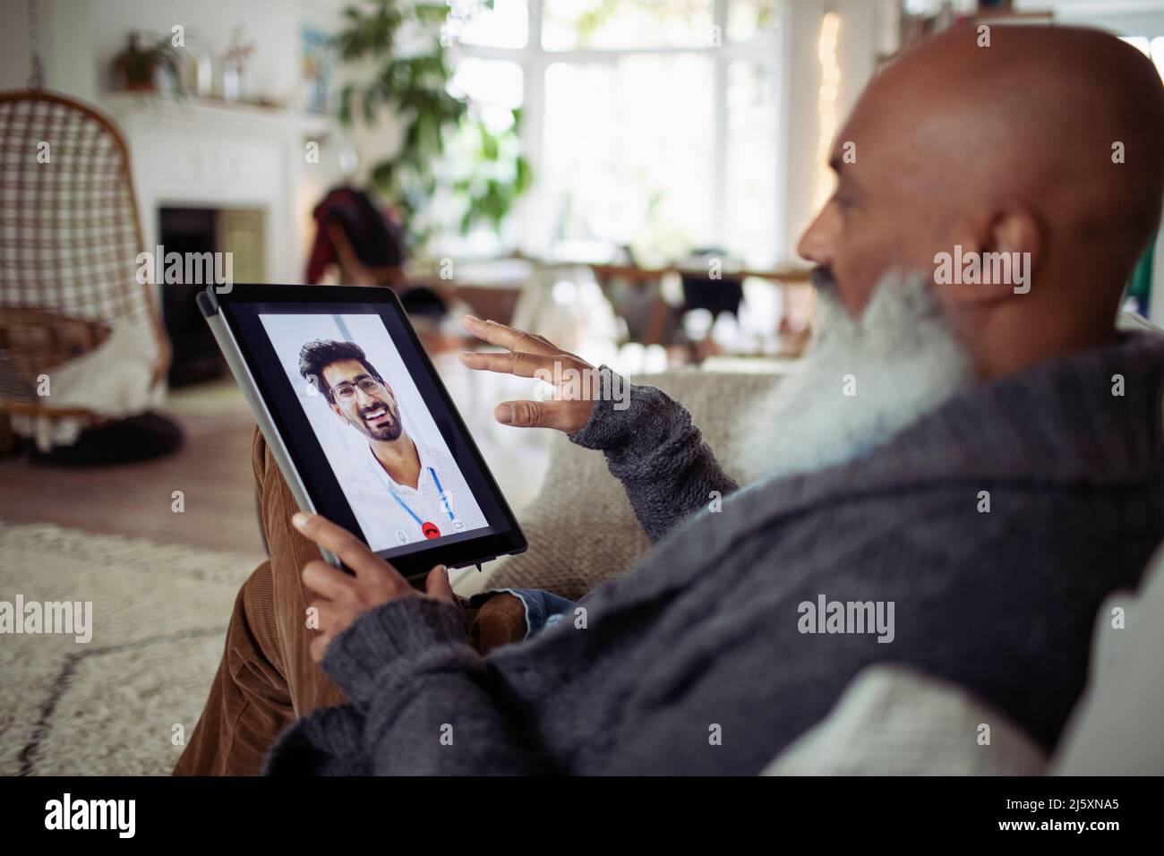 Uomo anziano che parla con il medico sullo schermo del tablet digitale Foto Stock