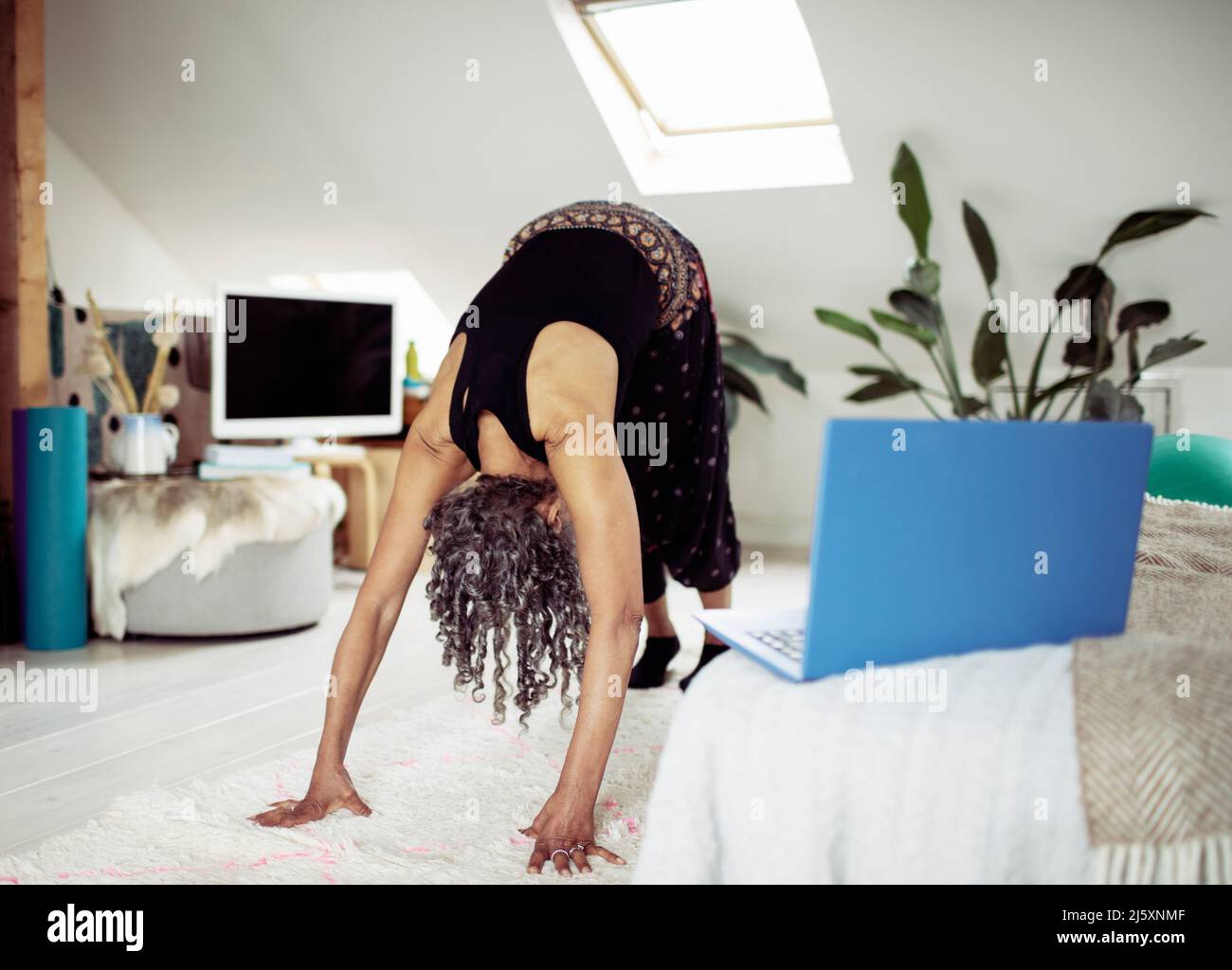 Donna anziana che pratica yoga online a casa Foto Stock