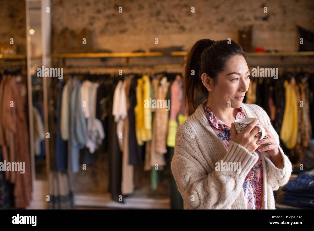 Donna di speranza negozio di abbigliamento proprietario bere tè Foto Stock