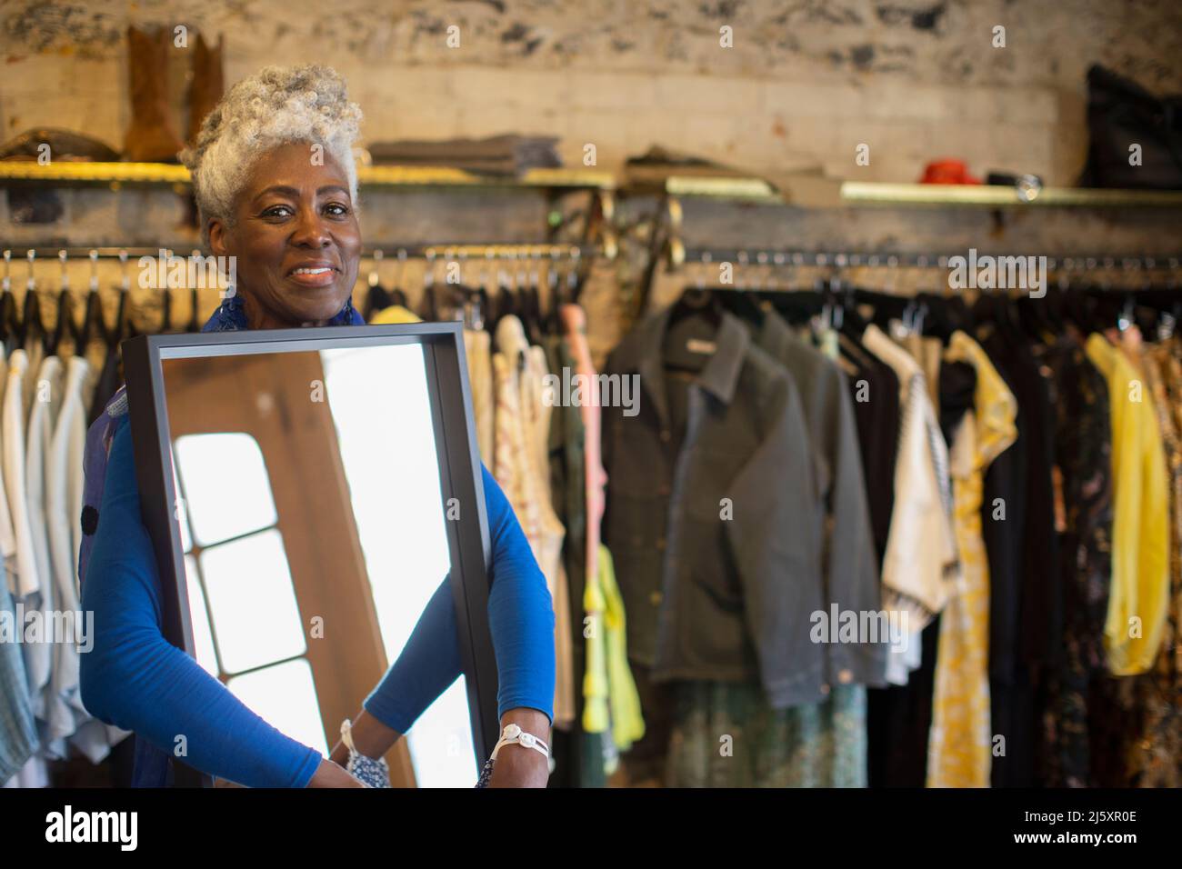 Ritratto fiducioso donna donna negozio proprietario con specchio in boutique Foto Stock