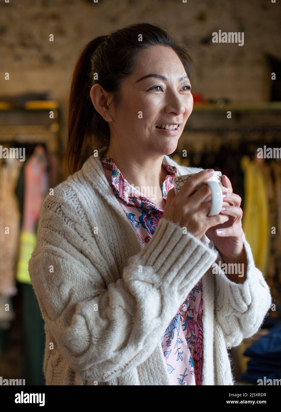 Donna felice bere caffè in negozio Foto Stock