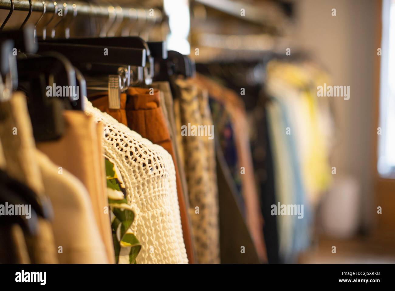 Vestiti appesi su scaffali in boutique di abbigliamento Foto Stock