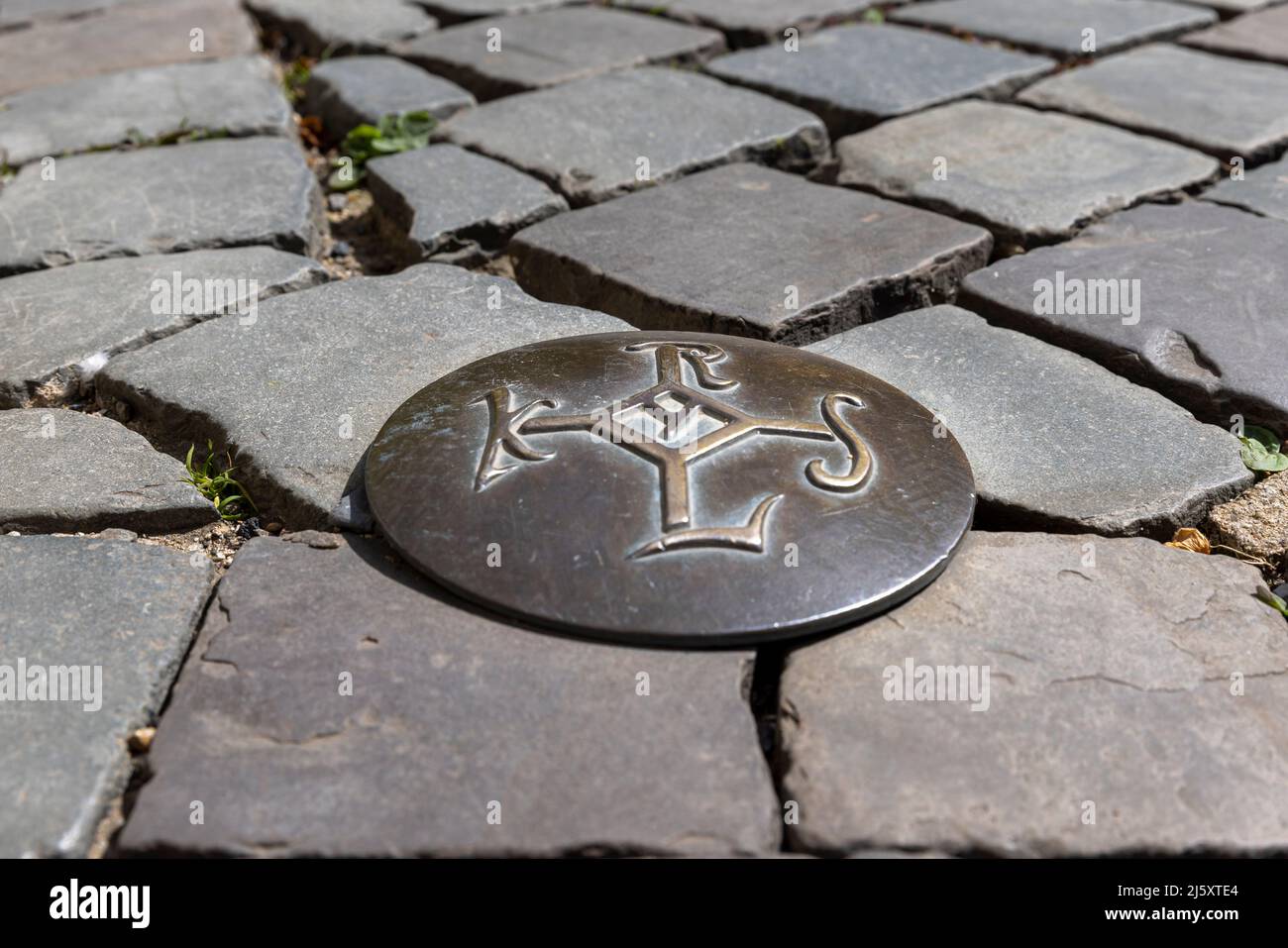 Aachen, Germania - Apr 18th 2022: Karolus Monogramm era il simbolo ufficiale di Karl il Grande. I simboli in bronzo conducono un percorso attraverso la vecchia t di Aquisgrana Foto Stock