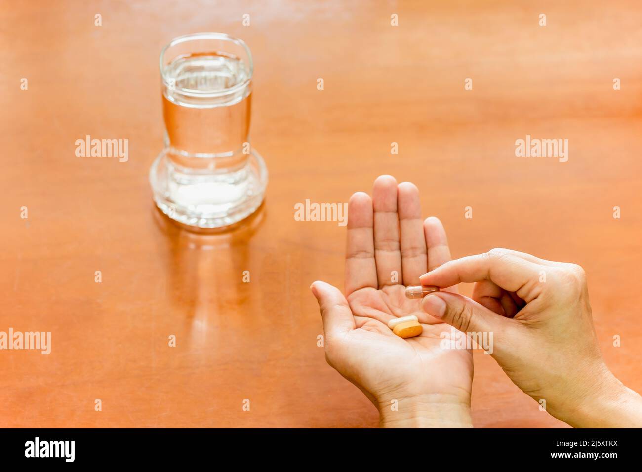 Donna mano che tiene pillole di medicina con vetro di acqua. Foto Stock