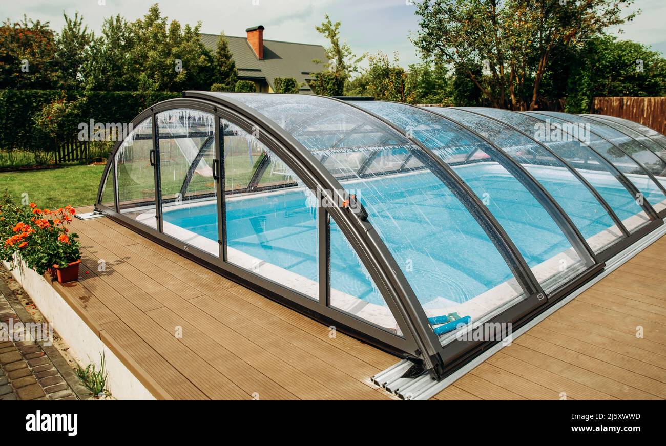 Piscina squisita con rivestimento trasparente. Area salotto in giardino. Foto Stock