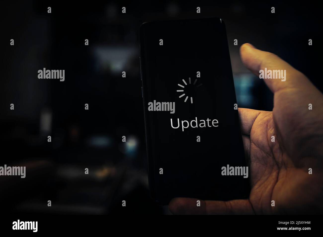 aggiornamento in linea del sistema operativo o delle applicazioni sullo schermo dello smartphone. Un giovane uomo sta tenendo uno smartphone nelle sue mani. Foto Stock