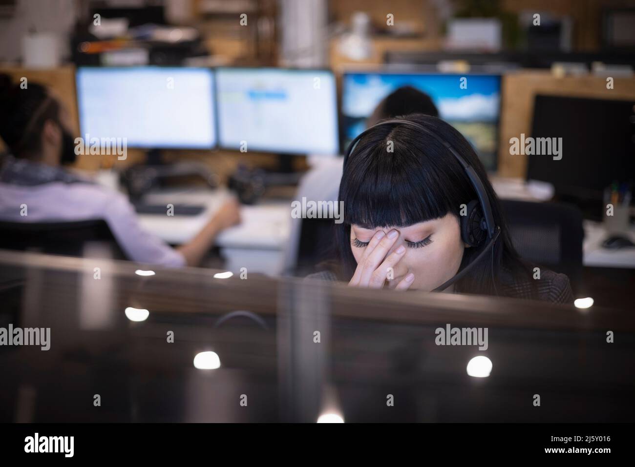 Donna d'affari stanca con la testa in mano alla scrivania d'ufficio Foto Stock