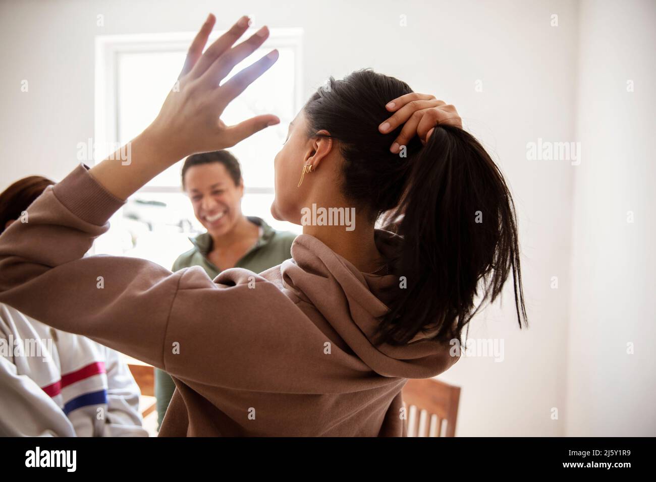 Giovane donna che tira i capelli indietro nel ponytail Foto Stock