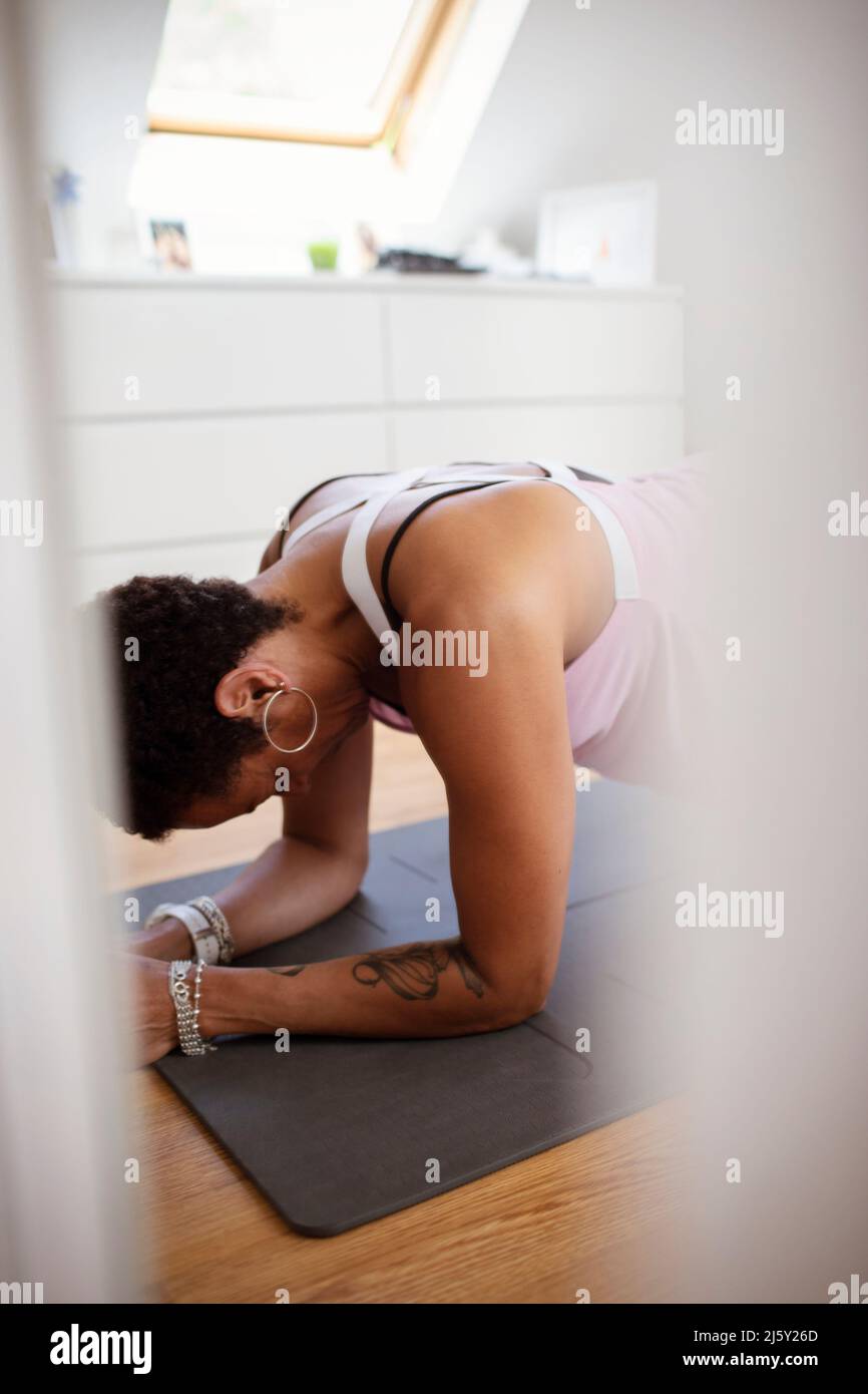 Donna che si esercita sul tappeto di yoga a casa Foto Stock