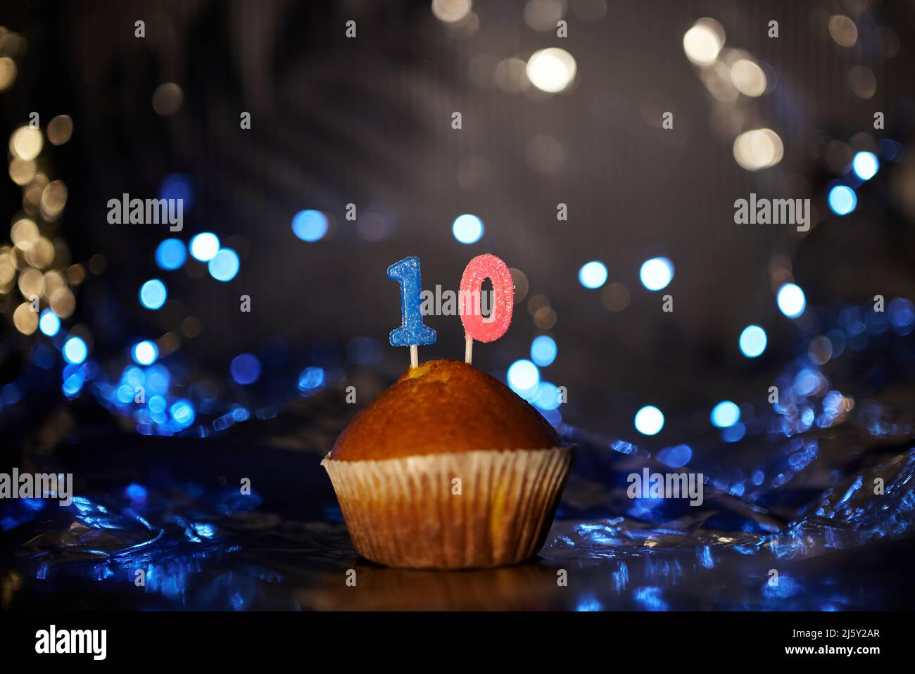 Cupcake o muffin fatti in casa gustosi con numero 10 TEN sul tavolo con foglio di alluminio e sfondo chiaro sfocato. Biglietto di auguri per compleanno o anniversario. Foto di alta qualità Foto Stock