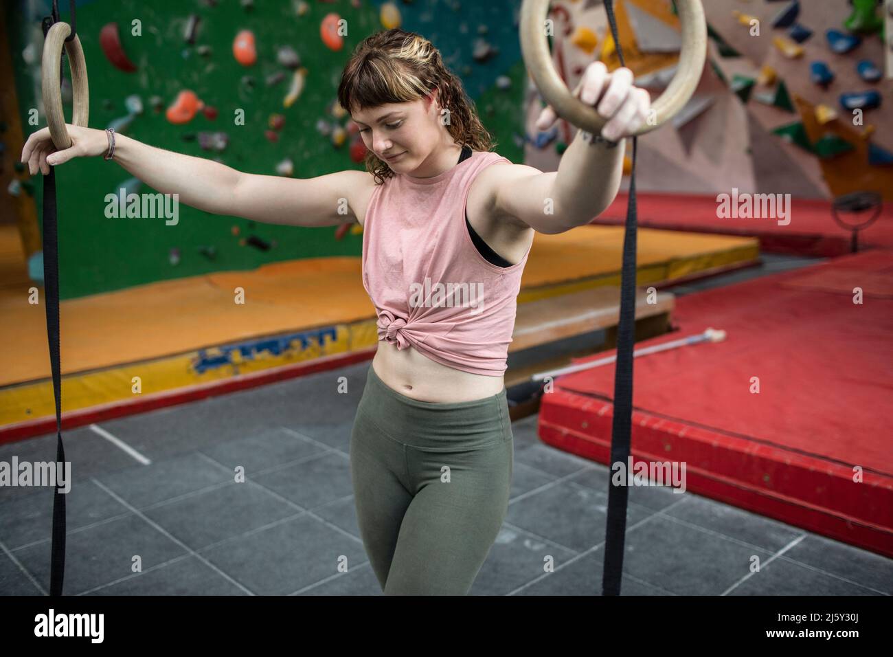 Giovane donna a ginnastica anelli in centro di arrampicata Foto Stock