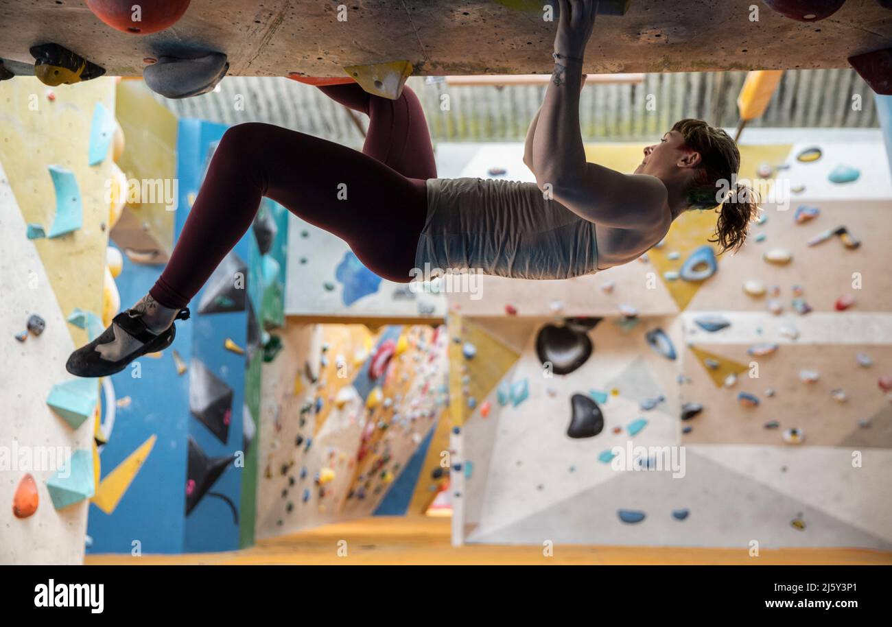 Giovane donna rock climbing capovolto Foto Stock