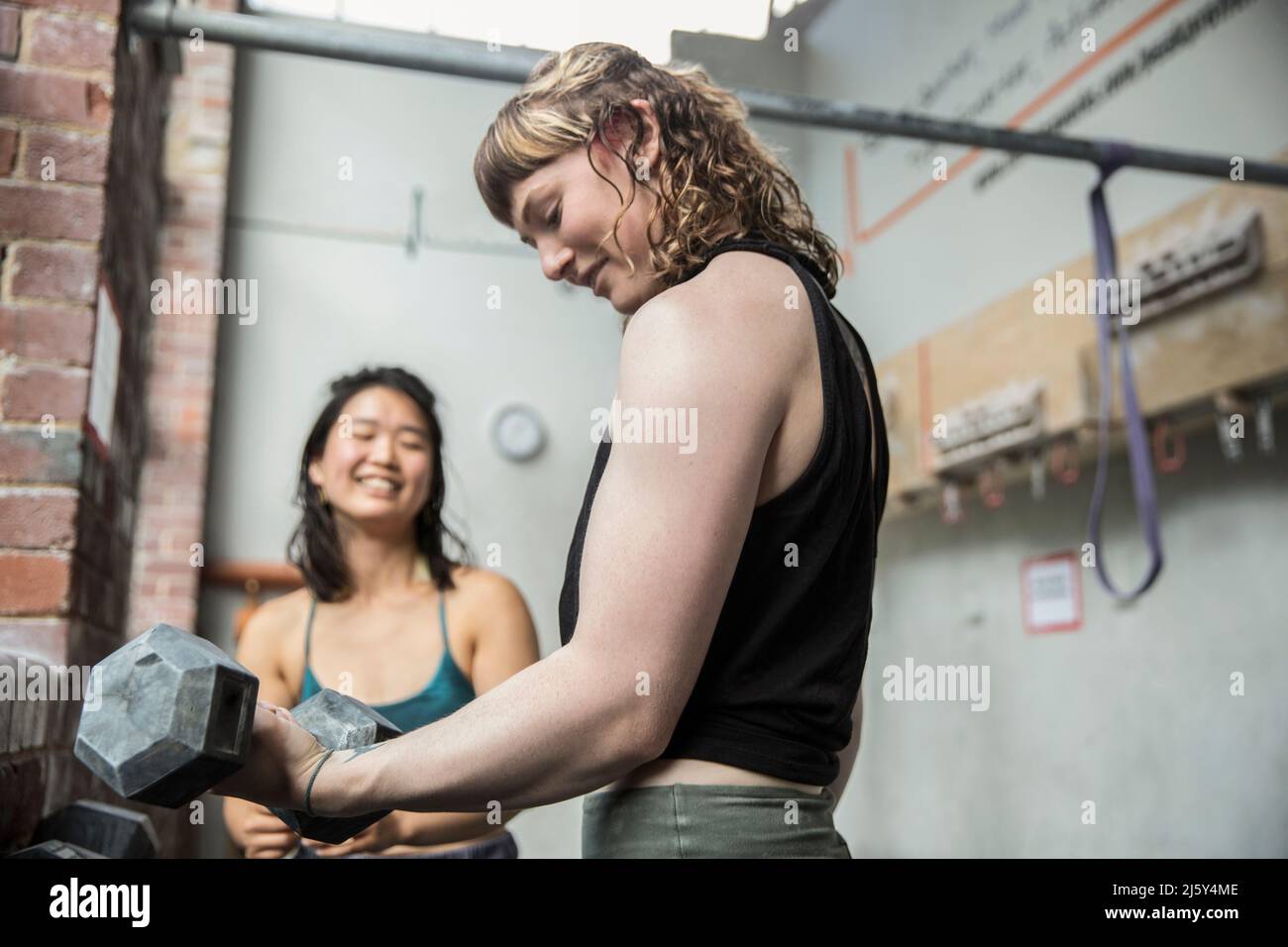 Giovane donna allenamento pesi con manubri in palestra Foto Stock