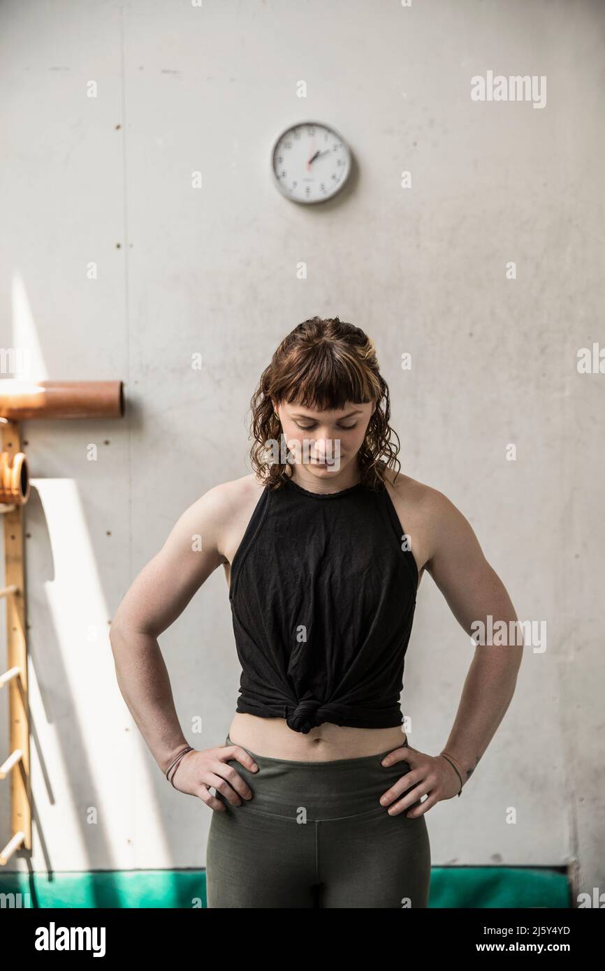 Giovane donna stanca che riposa con le mani sui fianchi in palestra Foto Stock
