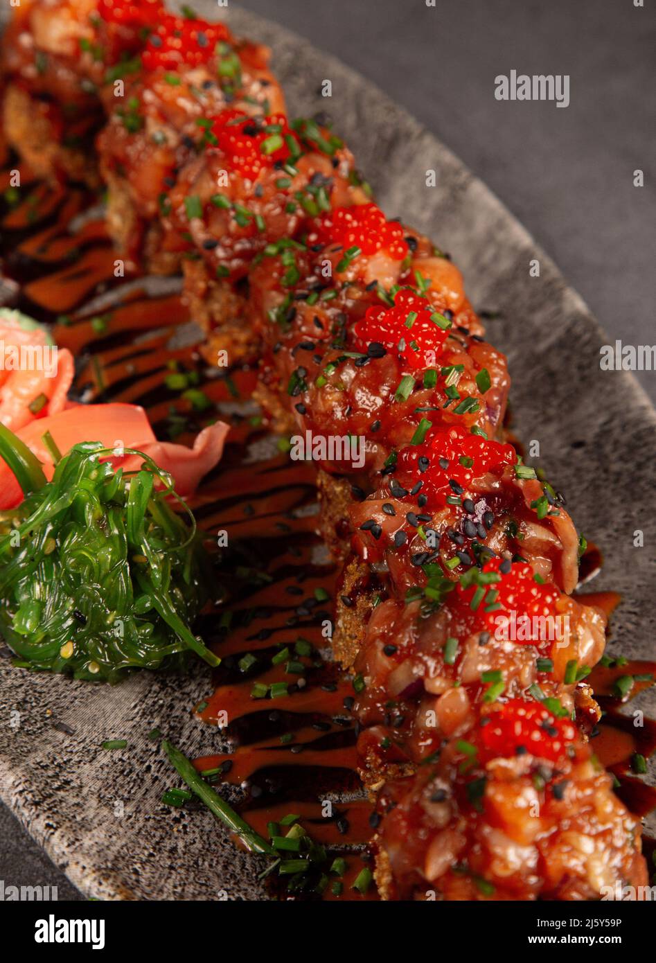 Da sopra di appetitosi sushi roll con caviale rosso e salmone serviti su piatto con insalata di wakame nel ristorante Foto Stock